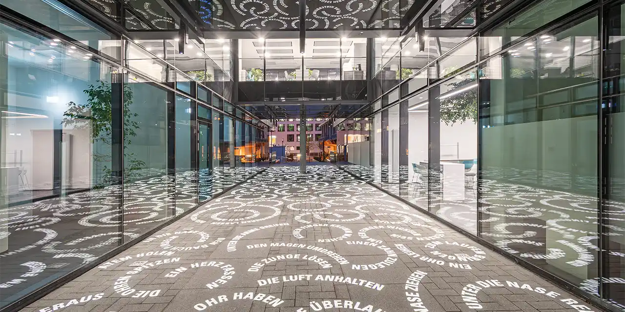 Lichtinstallation von Hartung & Trenz im Durchgang des ZMMK-Gebäudes der Kölner Uniklinik. Projektionsleuchten von Derksen Lichttechnik GmbH.